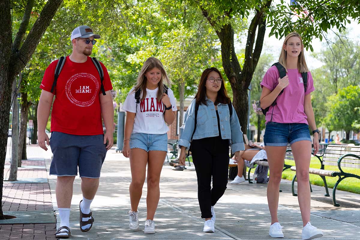 Four Miami students walking together through sidewalks in Uptown Oxford, near the Uptown Parks.