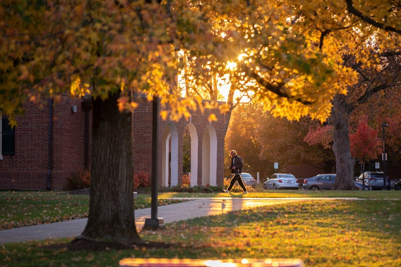 student walking on campus on a fall evening